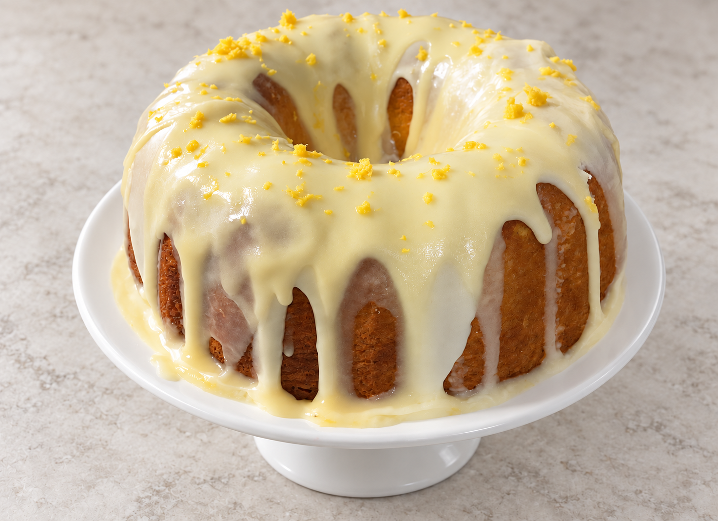 Lemon Bundt cake topped with a smooth glaze and lemon zest on a white cake plate
