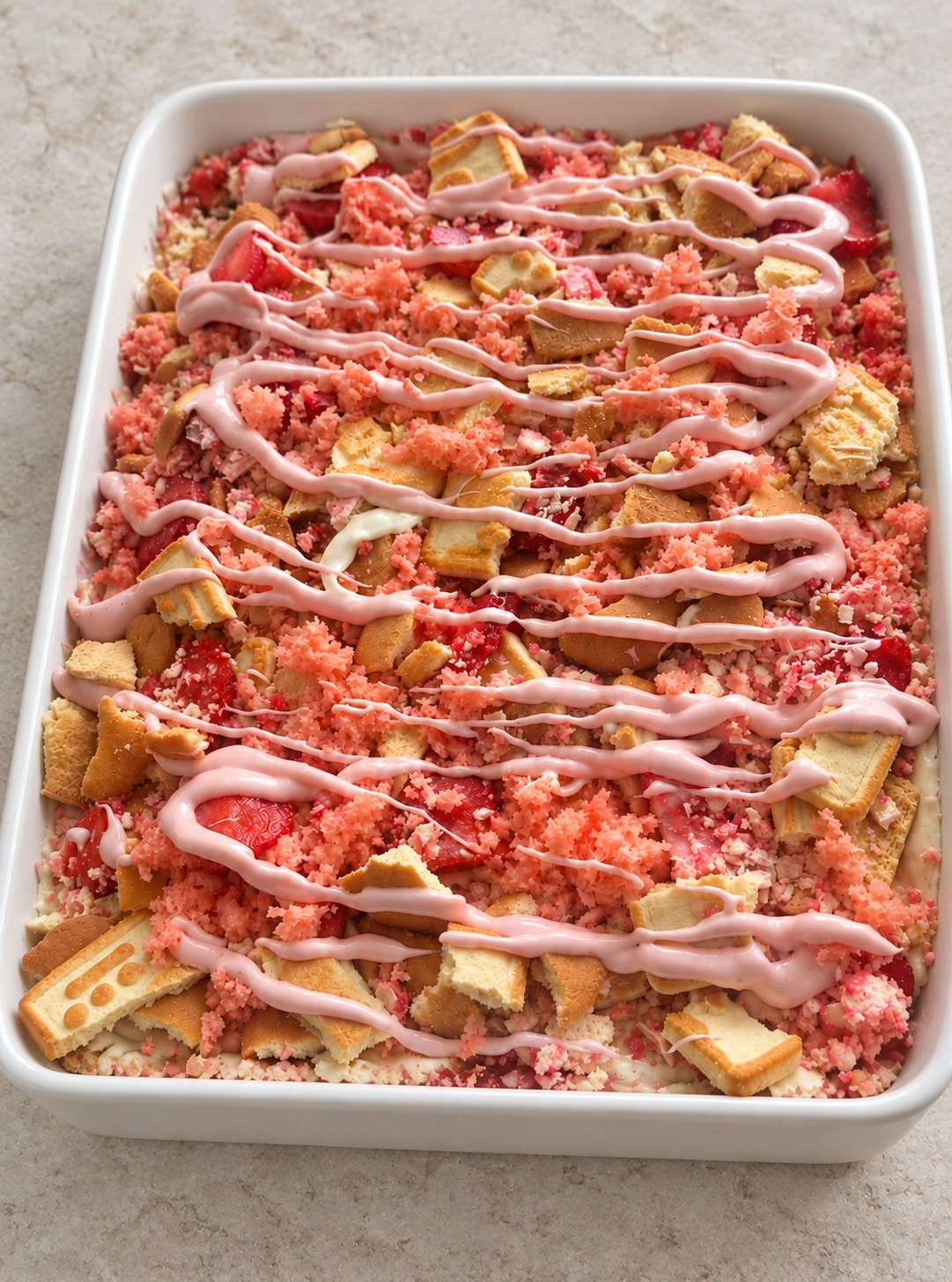 Strawberry dessert with cookies, pink crumble and drizzle in a white serving dish